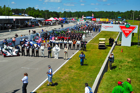 Team members line up on the grid for national anthems